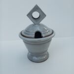Lidded jam pot with hole for a spoon in the lid.