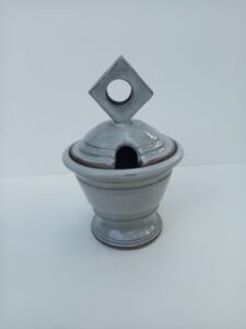 Lidded jam pot with hole for a spoon in the lid.